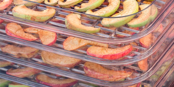 Green and red apple slices stacked in clear plastic trays